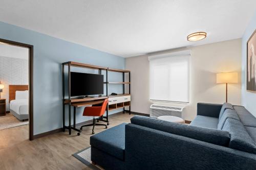 a living room with a couch and a desk with a television at Everhome Suites Chandler Phoenix Fashion Center in Chandler
