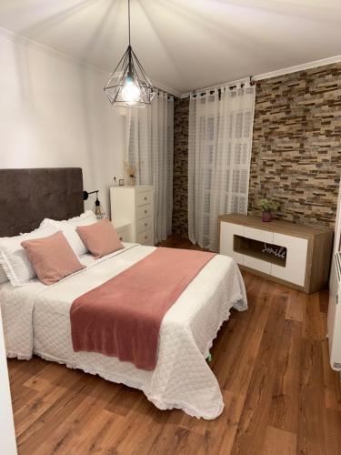 a bedroom with a large bed and a brick wall at Piso Praia da Rocha in Serres