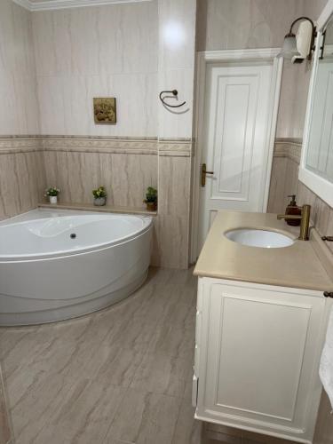a white bathroom with a tub and a sink at Piso Praia da Rocha in Serres