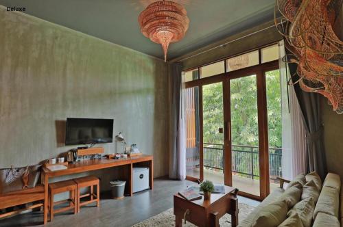 a living room with a couch and a table and a television at The Buffalo Amphawa in Samut Songkhram
