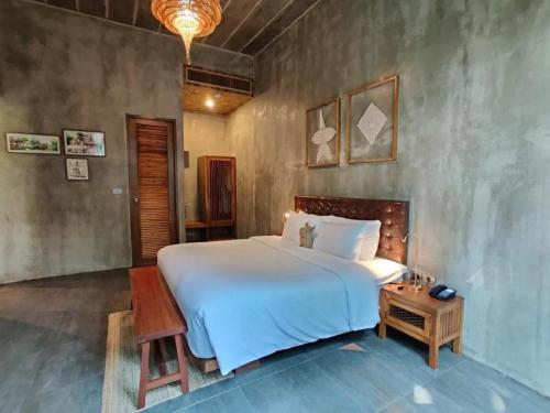 a bedroom with a large white bed and a table at The Buffalo Amphawa in Samut Songkhram