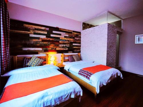 a bedroom with two beds and a brick wall at Spring Flowers Blossoming Hotel in Yangshuo