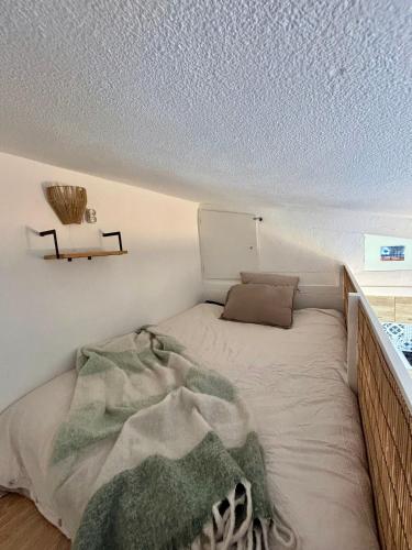 une chambre avec un lit avec une couverture dessus dans l'établissement Studio Cosy à 200m de la plage, au Barcarès