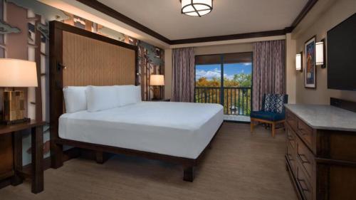 a bedroom with a large white bed and a balcony at Disney's Wilderness Lodge in Orlando