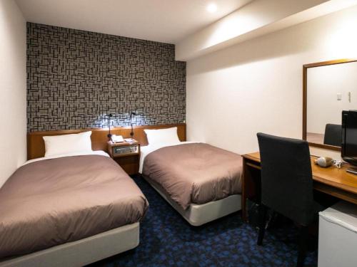 a hotel room with two beds and a desk and a computer at Green Hill Hotel Urban in Kobe