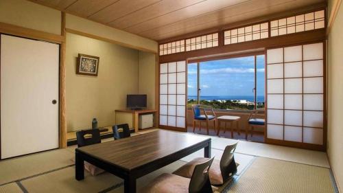a living room with a table and a view of the ocean at Kannawa Onsen Hotel Sansuikan in Beppu
