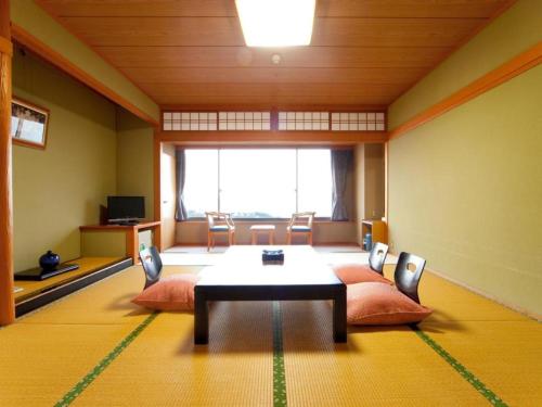 a room with a table and chairs and a large window at Kannawa Onsen Hotel Sansuikan in Beppu