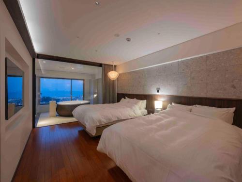 a bedroom with two beds and a bath tub in it at Kannawa Onsen Hotel Sansuikan in Beppu