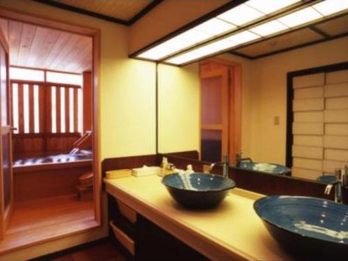 a bathroom with two sinks and a large mirror at Kannawa Onsen Hotel Sansuikan in Beppu