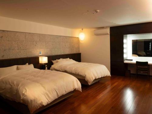 a hotel room with two beds and a mirror at Kannawa Onsen Hotel Sansuikan in Beppu