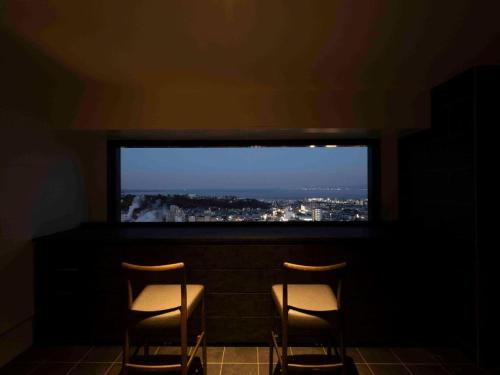 two chairs in a dark room with a large television at Kannawa Onsen Hotel Sansuikan in Beppu