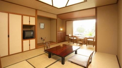 a living room with a table and chairs and a television at Hotel Tokoen in Yonago