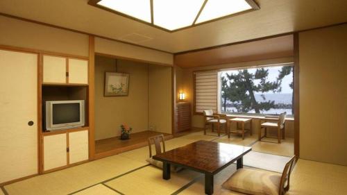 a living room with a table and a television at Hotel Tokoen in Yonago