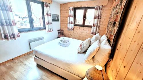 Cette petite chambre comprend un lit et deux fenêtres. dans l'établissement Résidence Week End - Appartement spacieux et lumineux, en plein centre MAE-2591, aux Gets