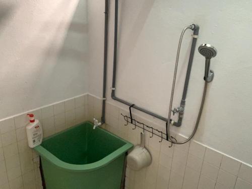 a shower in a bathroom with a green bucket at Lanang Islamic Homestay in Bedung