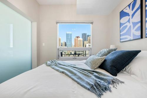 a bedroom with a large white bed with a window at Downtown Chic Retreat | Elegant + Free Parking in Calgary