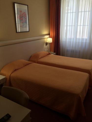 a hotel room with two beds and a window at Hotel Elysée in Lyon
