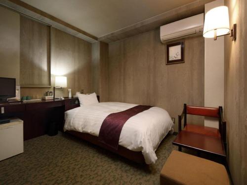 上田市Ueda Plaza Hotel的酒店客房配有一张床、一张书桌和一台电视。