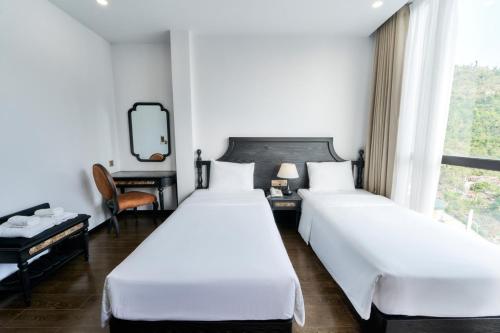 two beds in a hotel room with a window at Eden Hotel Cát Bà in Cat Ba