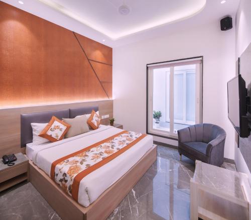 a bedroom with a bed and a chair and a window at Hotel Star Suites By Star Group in New Delhi