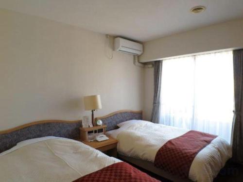 a hotel room with two beds and a window at Hotel Tenchikaku in Hitachi