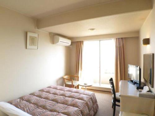 a hotel room with a bed and a television at Hotel Tenchikaku in Hitachi
