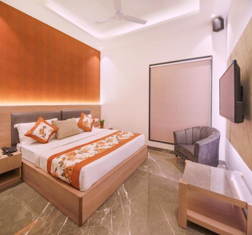 a bedroom with a bed and a tv and a chair at Hotel Star Suites By Star Group in New Delhi