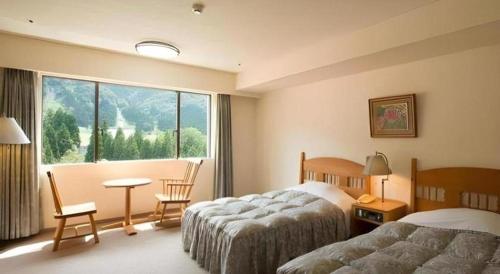 富山Tateyama Kokusai Hotel的酒店客房设有两张床和大窗户。