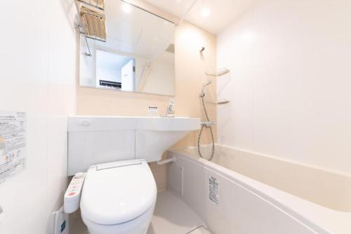 a bathroom with a toilet and a sink and a tub at E Hotel Kumagaya Annex in Kumagaya