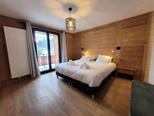 - une chambre avec un grand lit et des murs en bois dans l'établissement Résidence Le Nantaux - Appartement lumineux, dans un chalet entièrement rénové, centre station MAE-0931, aux Gets