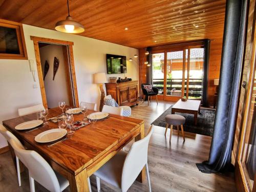 une salle à manger avec une table en bois et des chaises blanches dans l'établissement Résidence Le Plein Sud - très bel appartement classé 4, rénové avec soin et bien équipé MAE-1011, aux Gets