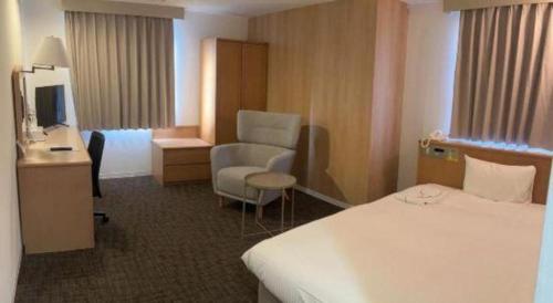 a hotel room with a bed and a chair at Business Hotel Nishiura Yokkaichi in Yokkaichi