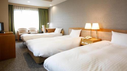a hotel room with three beds and a phone at Ako Park Hotel in Ako