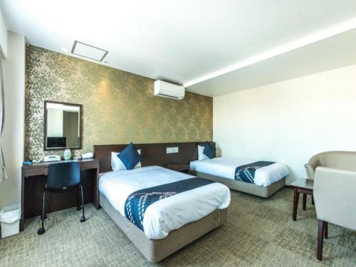 a hotel room with two beds and a desk at Tabist City Hotel Higashi-Matsuyama in Higashimatsuyama