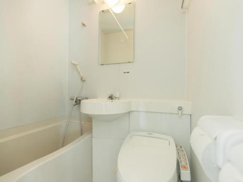 a white bathroom with a toilet and a sink at Tabist City Hotel Higashi-Matsuyama in Higashimatsuyama