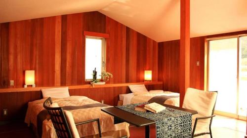 a hotel room with two beds and a table and chairs at Ukawa Onsen Yoshino no sato in Kyotango