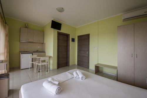 a bedroom with a white bed and a kitchen at Kanali Village Parga in Parga