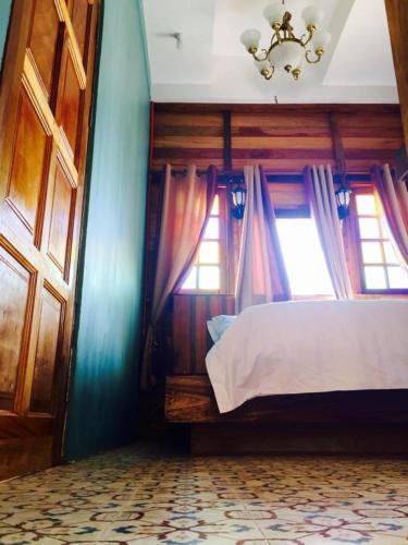 a bedroom with a bed and two windows and a chandelier at Kampong Pinang Sebatang Melaka in Melaka