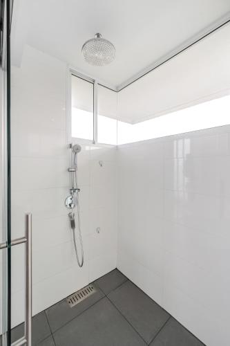 a bathroom with a shower in a white wall at Pure Sunset Beach - Ocean View Room, Pattaya in Na Jomtien
