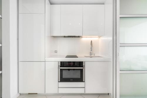 a white kitchen with a sink and a microwave at Pure Sunset Beach - Ocean View Room, Pattaya in Na Jomtien