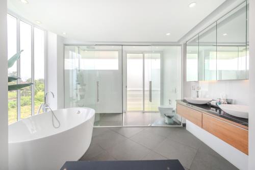a white bathroom with two sinks and a tub at Pure Sunset Beach - Ocean View Room, Pattaya in Na Jomtien