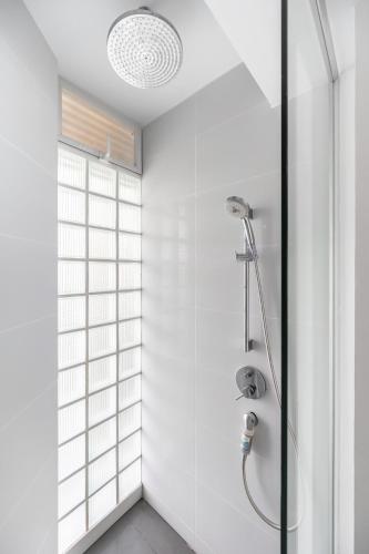 a white bathroom with a shower with a glass door at Pure Sunset Beach - Ocean View Room, Pattaya in Na Jomtien