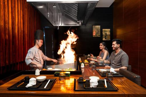 a group of people sitting around a table with a fire at DoubleTree by Hilton-Pune Chinchwad in Pune
