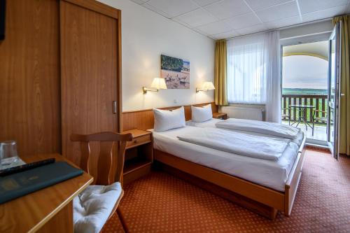 a bedroom with a bed and a desk and a balcony at Hotel Rebschule in Freyburg