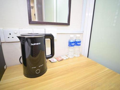 a black appliance sitting on a counter with two bottles of water at My Home Hotel Wangsa Maju in Kuala Lumpur