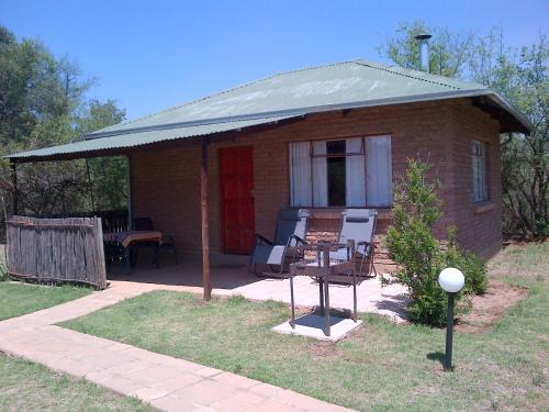 a small brick house with a porch and a table at Riverbend Self Catering Cottages in Magaliesburg