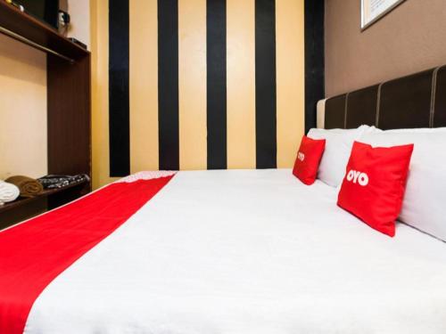 a large white bed with red pillows on it at OYO 44123 Hotel Al-Saif in Kuala Kerai