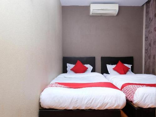 two beds in a room with red pillows at OYO 44123 Hotel Al-Saif in Kuala Kerai