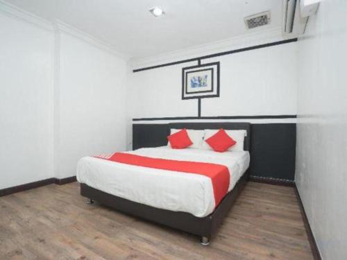 a bedroom with a large bed with red pillows at Capital O Ridel Hotel Kota Bharu in Kota Bharu