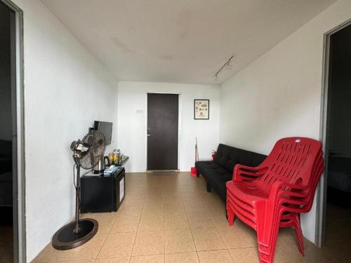a living room with a black couch and a red chair at Rockbund Fishing Chalet in Kampong Batu Gajah